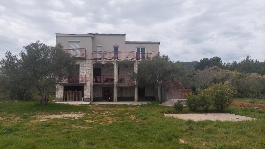 a large house with a balcony on top of a field at Adria in Pašman