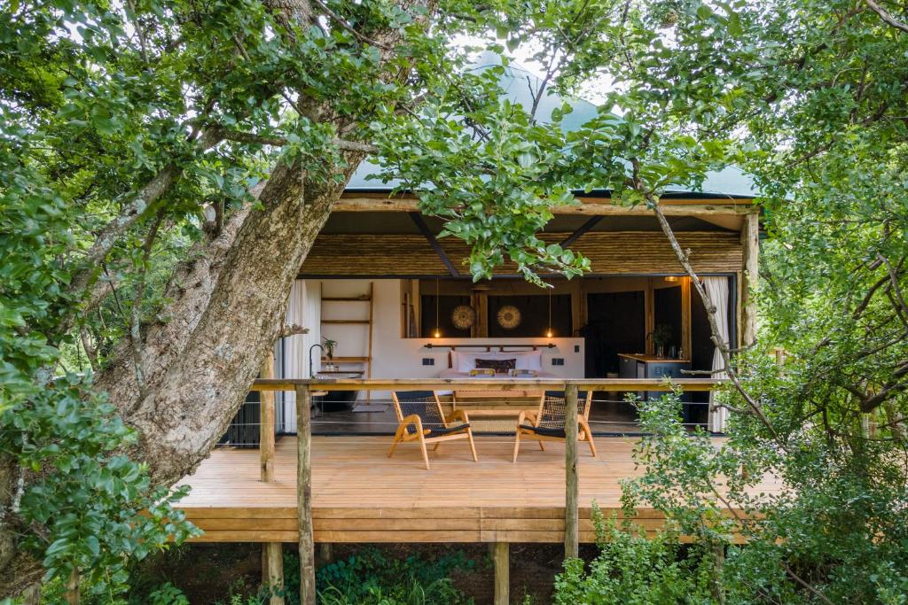a home with a wooden deck with a table and chairs at Sasi Africa Luxury Tented Bush Lodge in Bergville