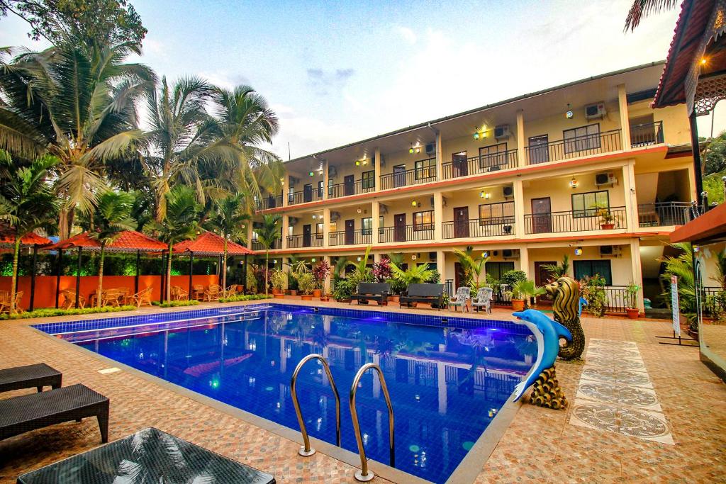 a hotel with a swimming pool in front of a building at FabEscape SK Studios With Pool & GYM, Arpora in Arpora