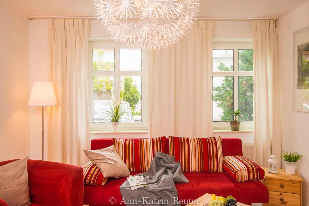 a living room with a red couch and windows at Ferienhaus am Ufer - Ferienwohnung Strandsand in Sassnitz