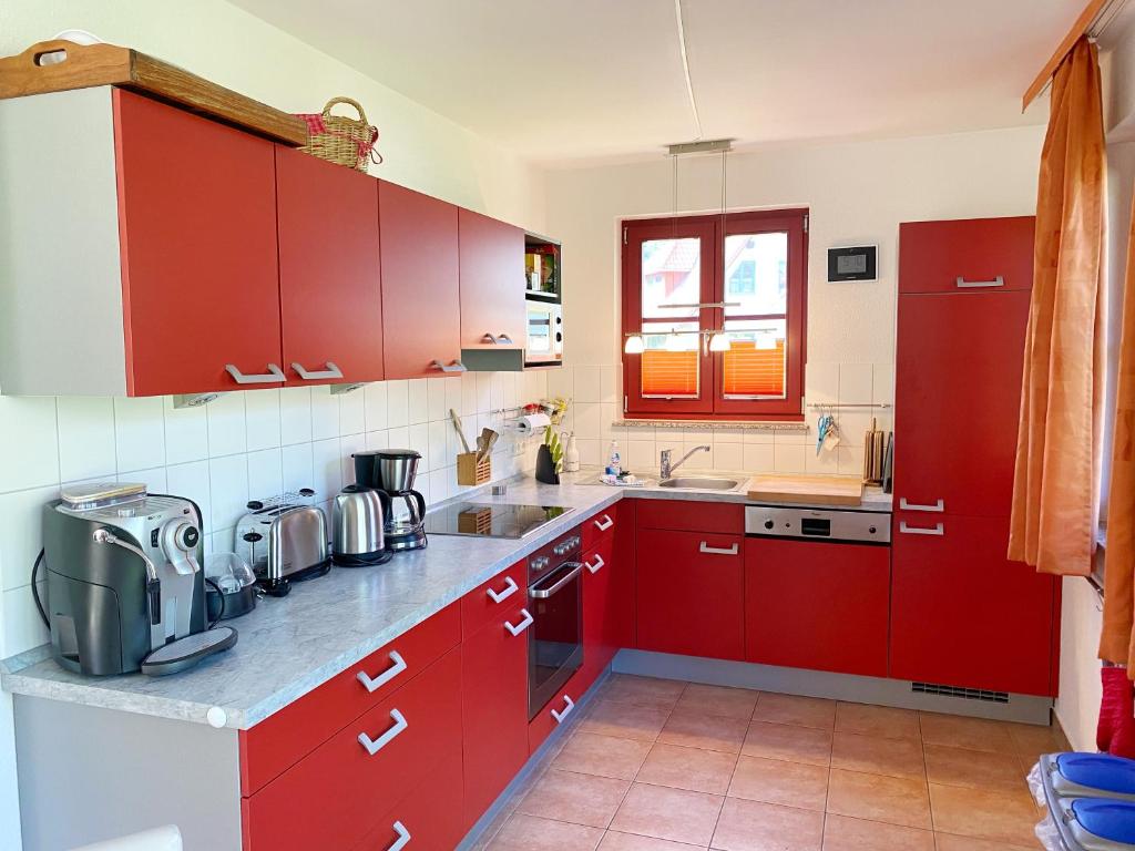eine rote Küche mit roten Schränken und einem Waschbecken in der Unterkunft Ferienhaus am Leuchtturm in Glowe