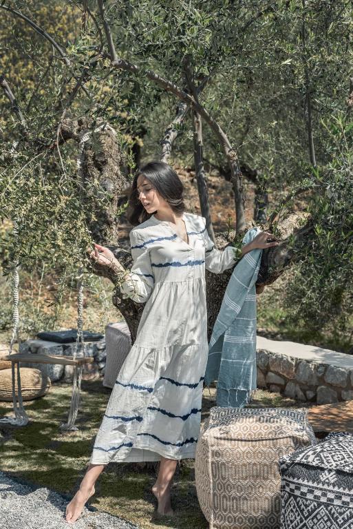 a woman in a dress standing next to a tree at The Olive Yard in Gythio