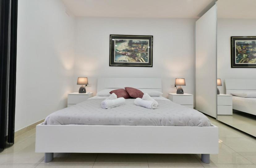 ein weißes Schlafzimmer mit einem Bett und zwei Handtüchern in der Unterkunft Sea view apartment in Birżebbuġa