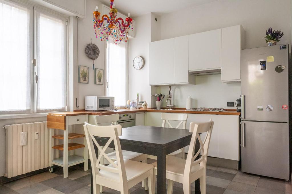 a kitchen with a table and chairs and a refrigerator at BnButler - Riccardo Galli - Incantevole Appartamento, Come a Casa Vostra! in Milan