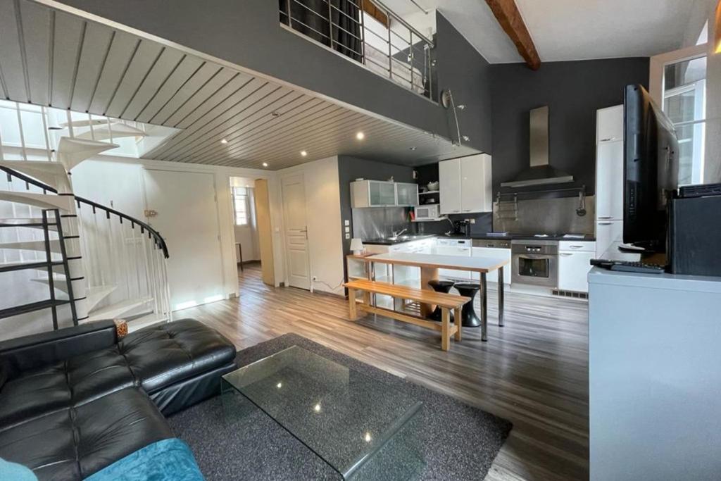 un salon avec un canapé noir et une cuisine dans l'établissement Riouffe 2 bedroom duplex apartment in the center of Cannes, à Cannes