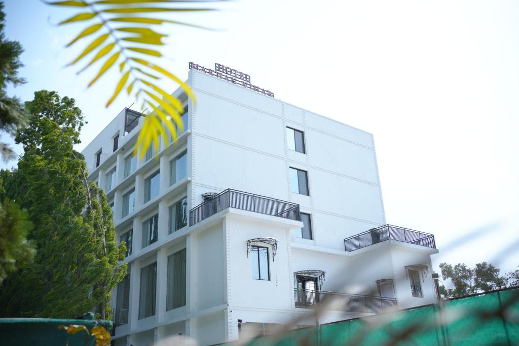 een wit gebouw met balkons aan de zijkant bij HOTEL MAKHAN VIHAR in Ambikāpur