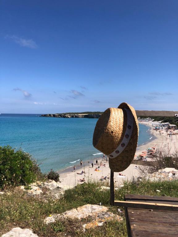 un sombrero de paja sentado en un banco junto a una playa en Casa di Max, en Torre dell'Orso