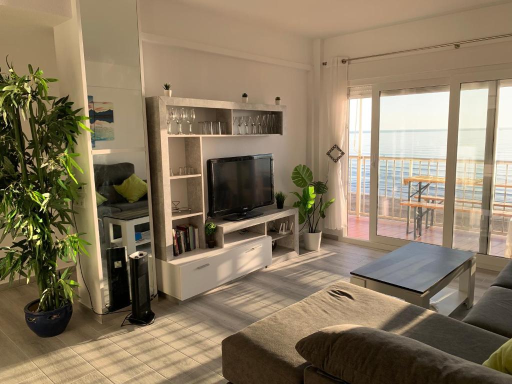 een woonkamer met een flatscreen-tv en een bank bij Primera línea en Cullera con piscina. Inmejorables vistas in Cullera