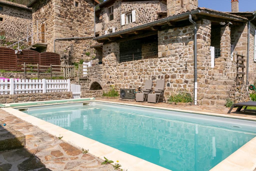 - une piscine en face d'un bâtiment en pierre dans l'établissement Château de Laulagnet, à Jaujac