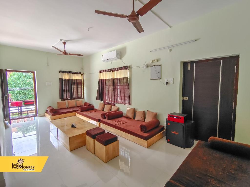 sala de estar con sofás y ventilador de techo. en BACPAC MONKEY COLIVING, en Visakhapatnam