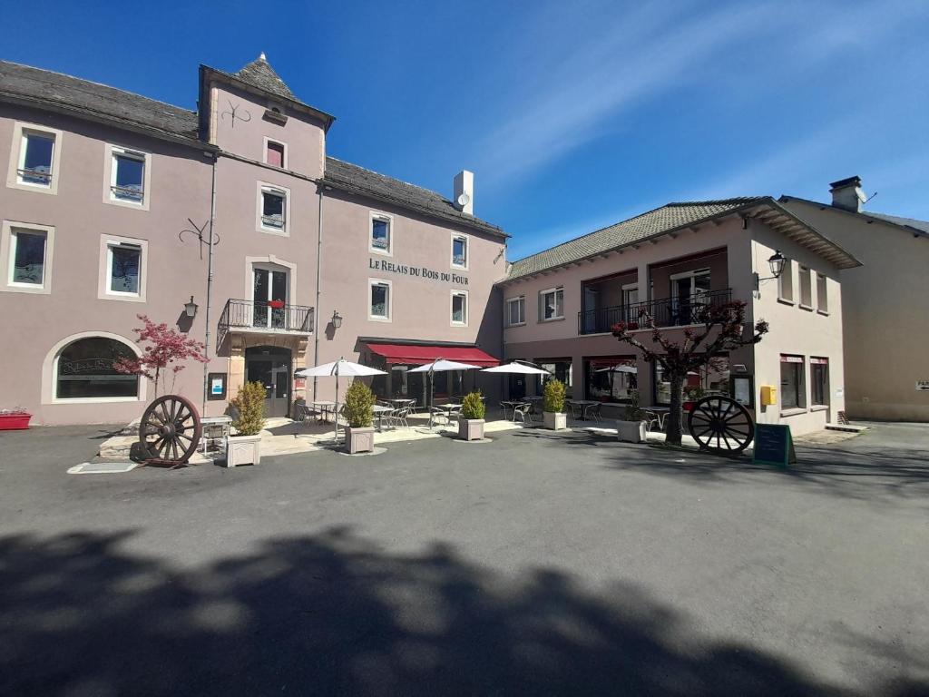 a group of buildings with umbrellas in a parking lot at Relais du Bois du Four in Saint-Léons