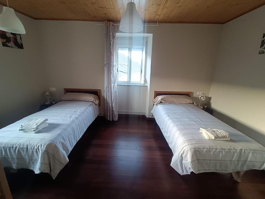 two beds in a room with a window at CASA ISAURA DE PENA Camino Primitivo in Pacio
