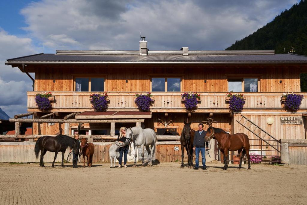 grupa ludzi stojących przed budynkiem z końmi w obiekcie B&B Margit's Ranch Urlaub am Pferdehof w mieście Silz