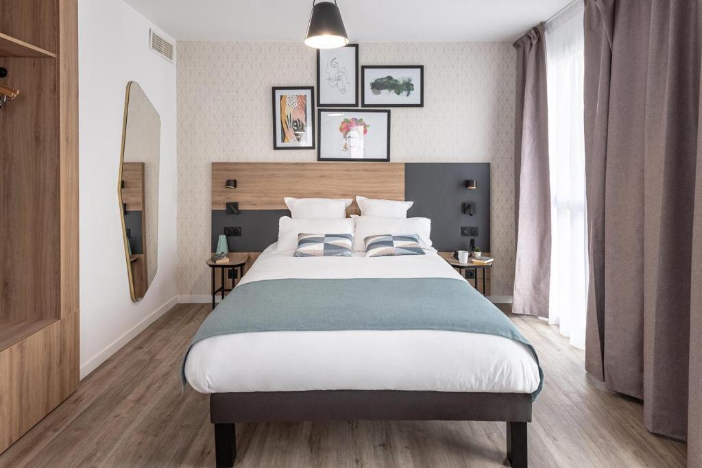 sypialnia z dużym łóżkiem i dwoma stołami w obiekcie Appart'City Collection Saint Germain en Laye w mieście Saint-Germain-en-Laye