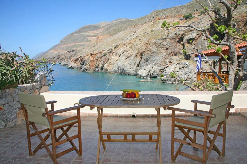 een tafel en stoelen met uitzicht op het water bij On The Beach Apartments in Khóra Sfakíon