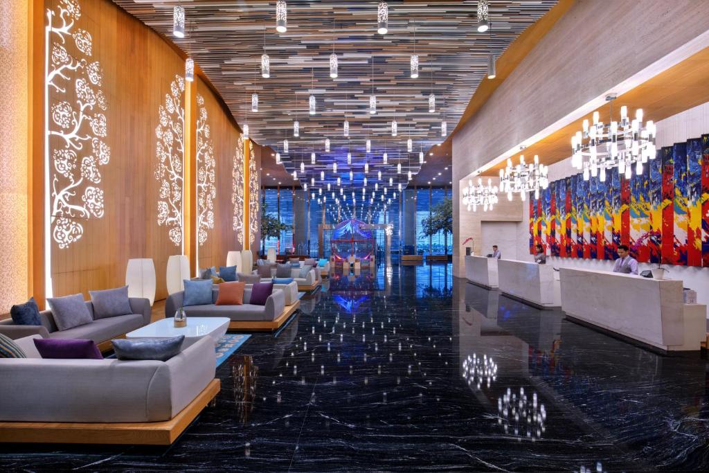 a lobby with couches and chandeliers in a building at Grand Mercure Jakarta Kemayoran in Jakarta