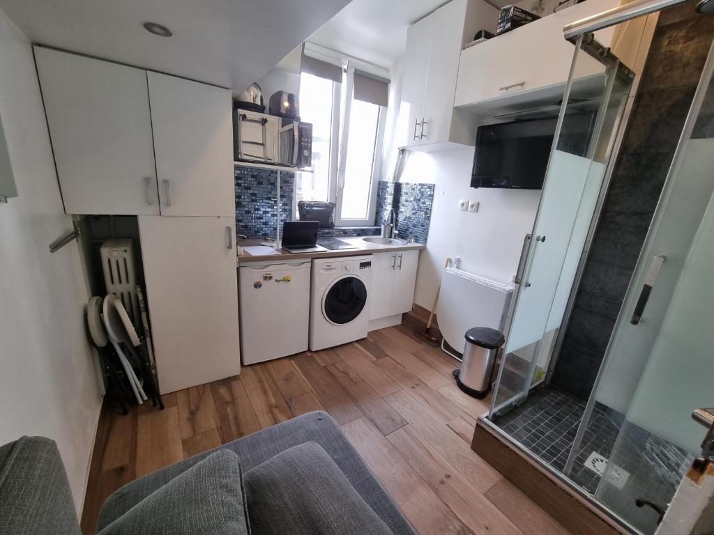 a small kitchen with white cabinets and a washer and dryer at Amazing Studio near Parc des Expositions in Paris