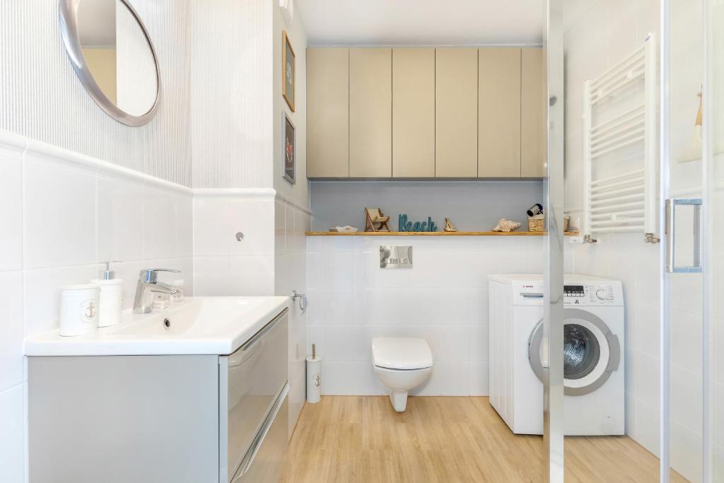 a white bathroom with a washing machine and a sink at Magic Marine Apartment in Dziwnówek