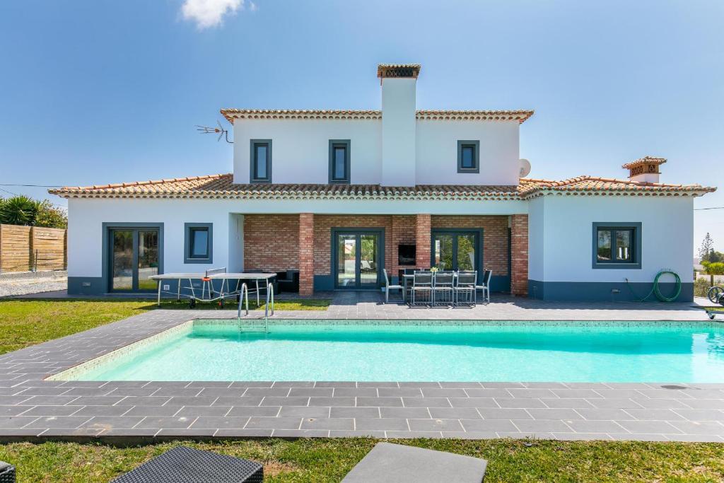 a villa with a swimming pool in front of a house at Casa Amizade in Aljezur