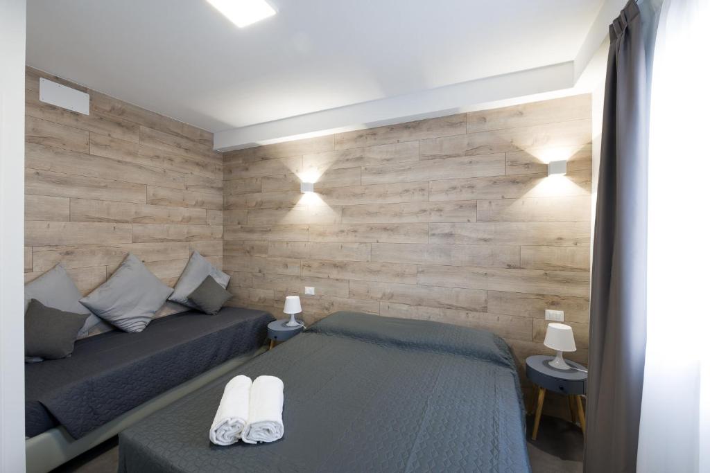 a bedroom with two beds and a wooden wall at Boutique Hotel Nuovo Cason in Cavallino-Treporti