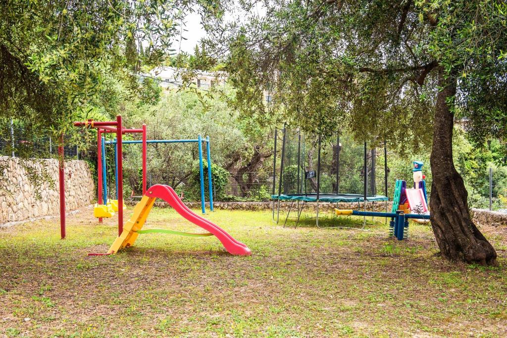 um parque infantil com escorrega e uma árvore em Bozikis Studios em Paleokastritsa
