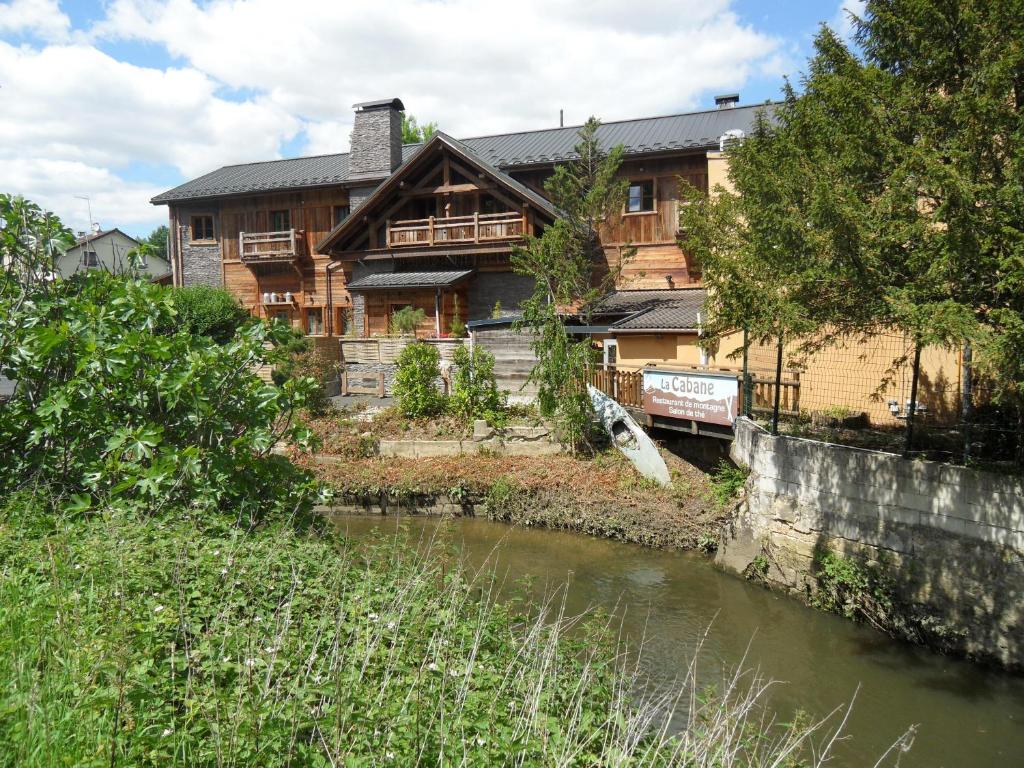 ein Holzhaus mit einem Fluss davor in der Unterkunft Le Moulin de Lily in Palaiseau