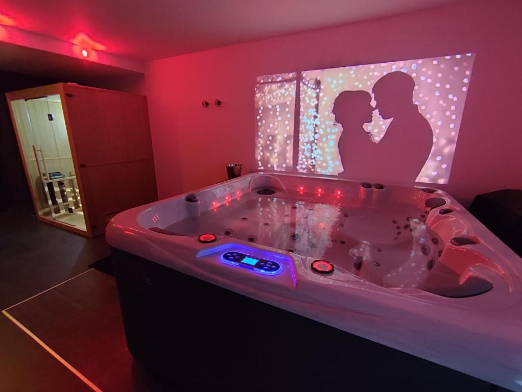 ein Badezimmer mit einer Badewanne mit einem Bild von einem Paar in der Unterkunft AVEC TOI suite spa in Barlin