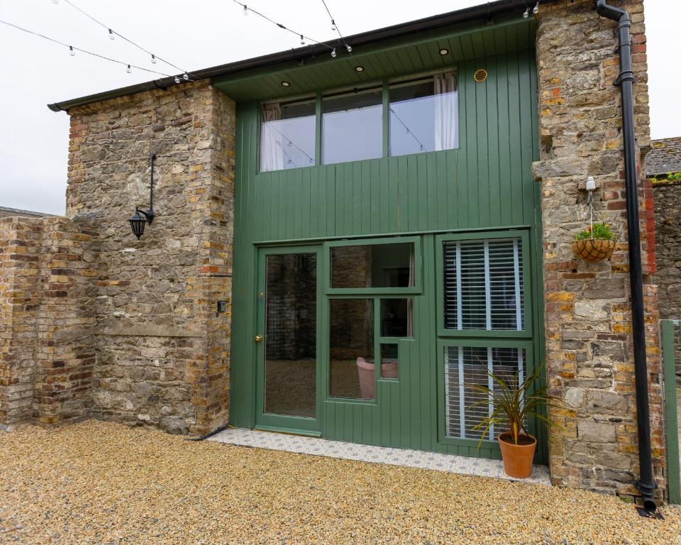 una casa verde con una pared de ladrillo y una puerta verde en Stay Barrow Blueway - The Stables, en Monasterevin