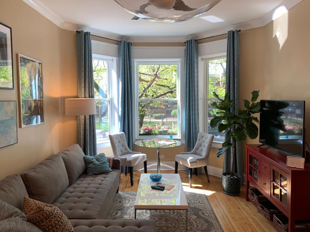 a living room with a couch and a table and windows at 1F Cozy Home in Little Italy near Downtown West Loop United Center in Chicago