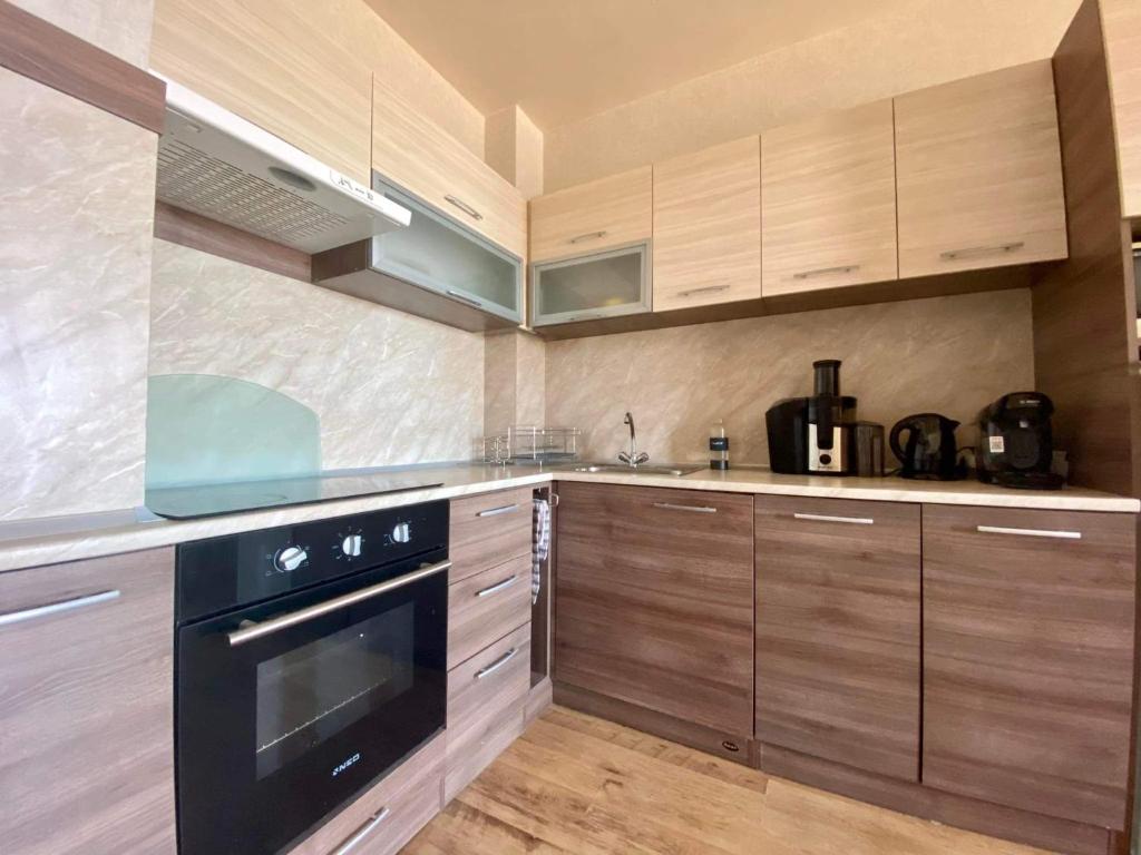 a kitchen with wooden cabinets and a black oven at Sozopol Dreams apartman 42 in Sozopol