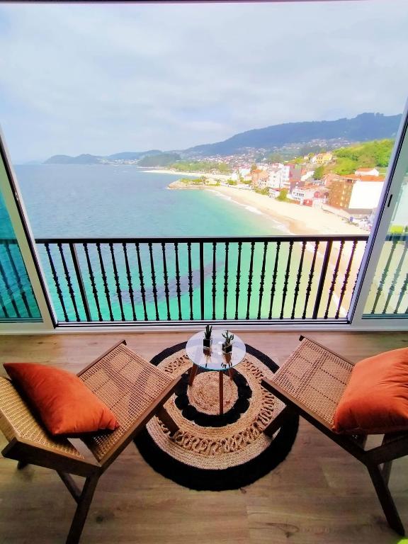balkon ze stołem i krzesłami oraz plażą w obiekcie Piso El Acantilado w mieście Bueu