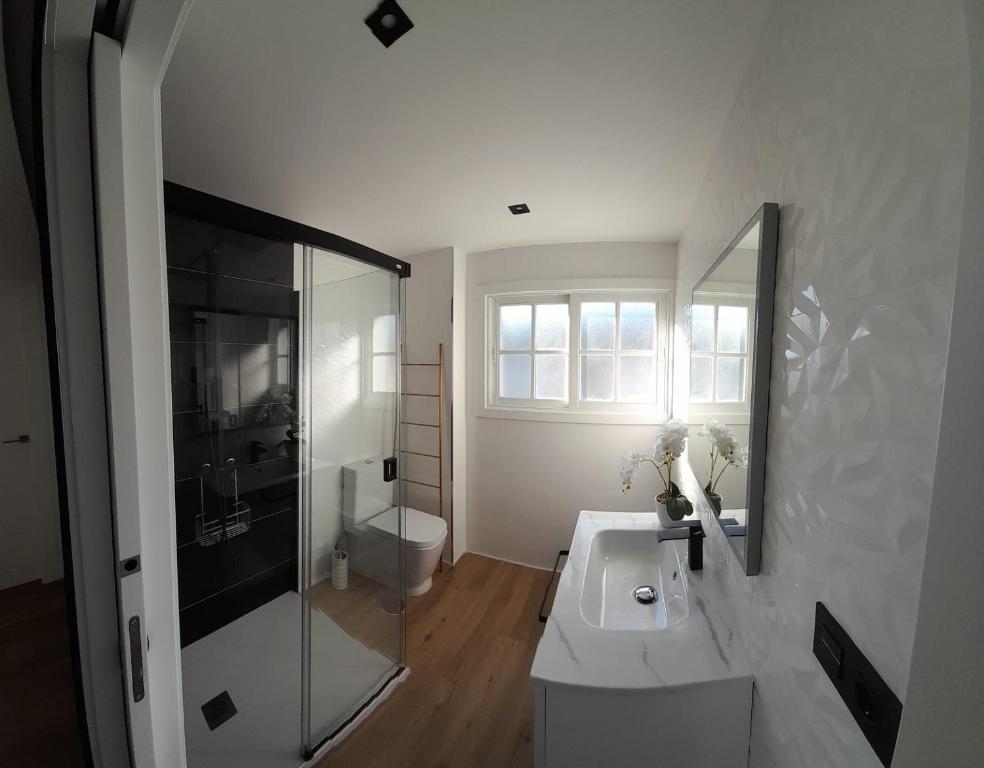 a white bathroom with a sink and a toilet at Piso El Acantilado in Bueu