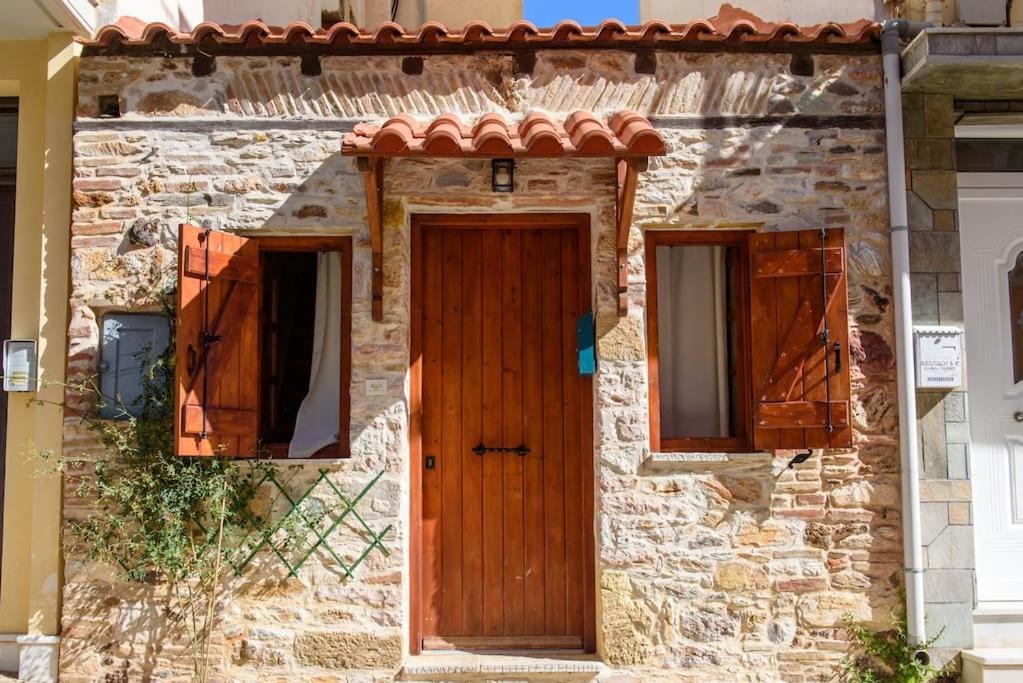 una casa in pietra con una porta in legno e due finestre di Lavrio stone house 5 min from the centre/port a Laurio