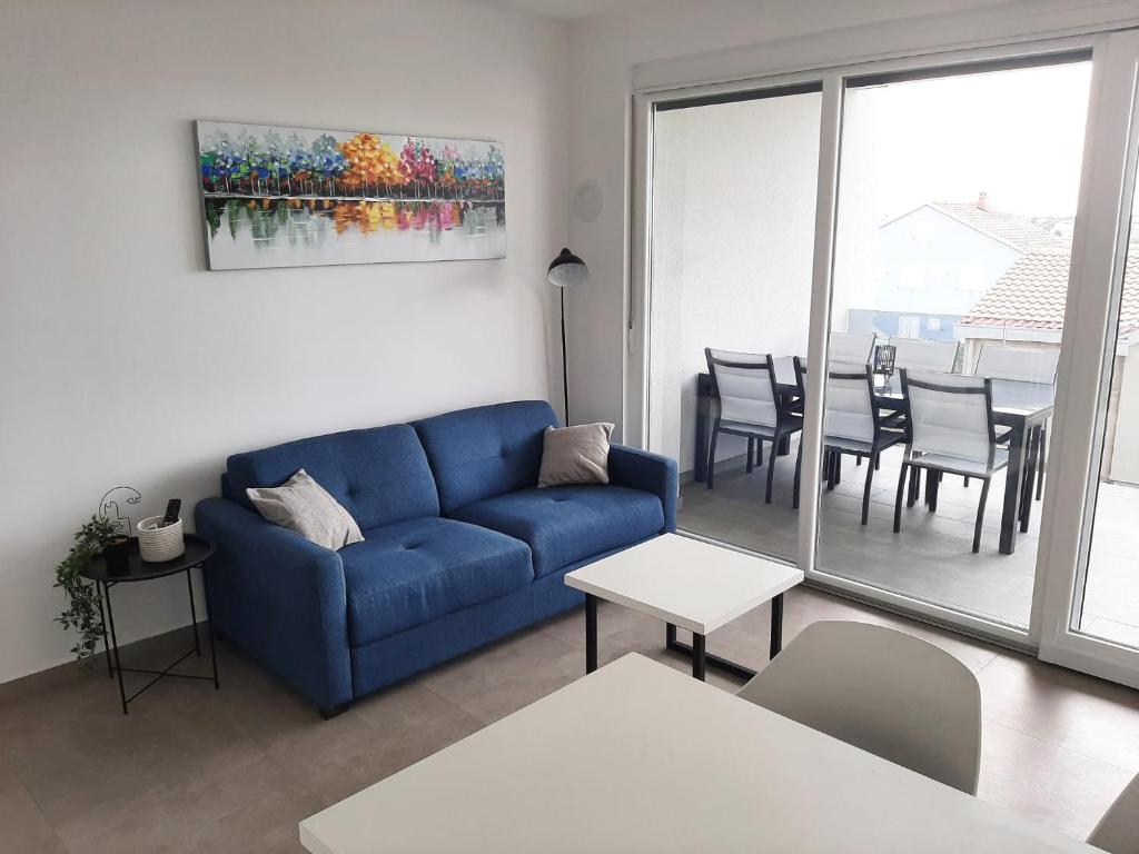 sala de estar con sofá azul y mesa en Apartments Anda Nin, en Nin
