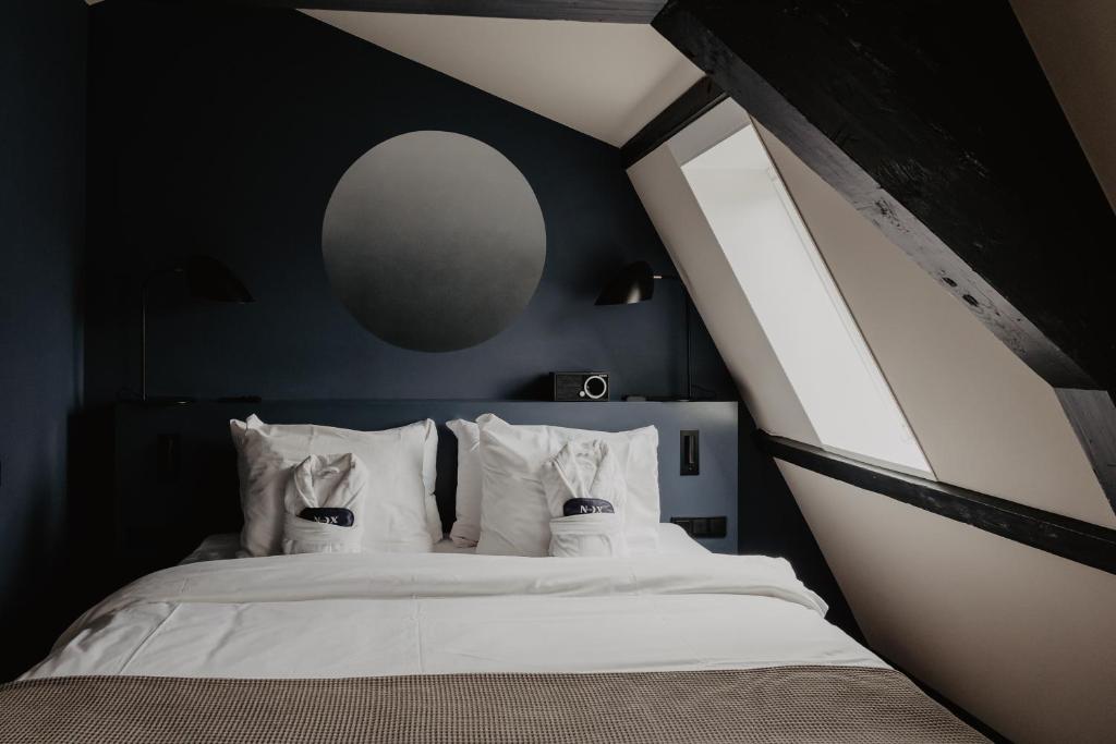 a bedroom with a white bed with a large window at The Nox Hotel in Utrecht