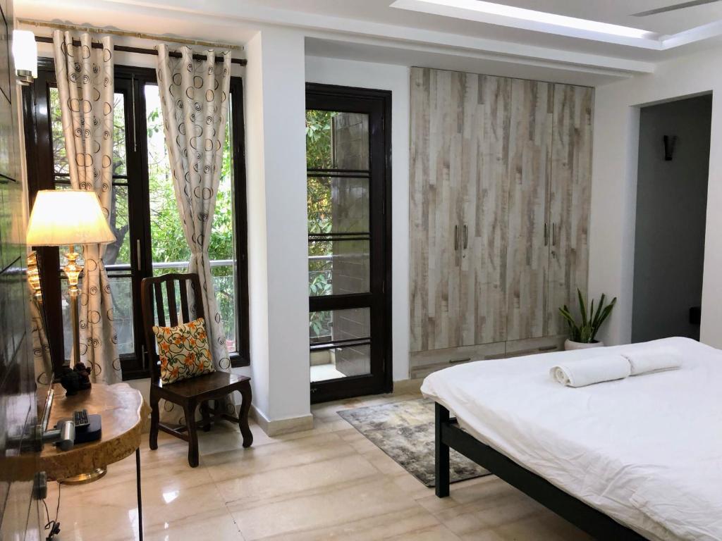 a bedroom with a bed and a desk and windows at Avatar Living @Safdarjung Enclave in New Delhi