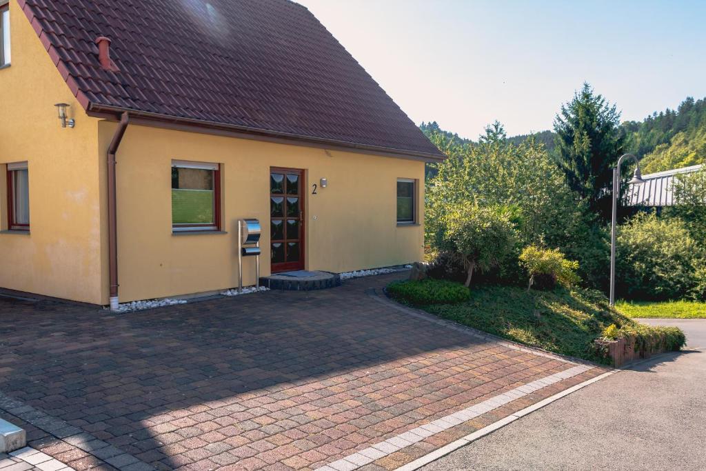 una casa amarilla con una entrada de ladrillo delante de ella en Ferienwohnung Le, en Adenau