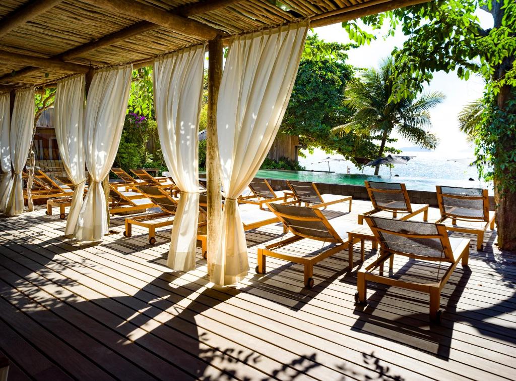 a group of chairs sitting on a wooden deck at TW Guaimbê Exclusive Suítes in Ilhabela