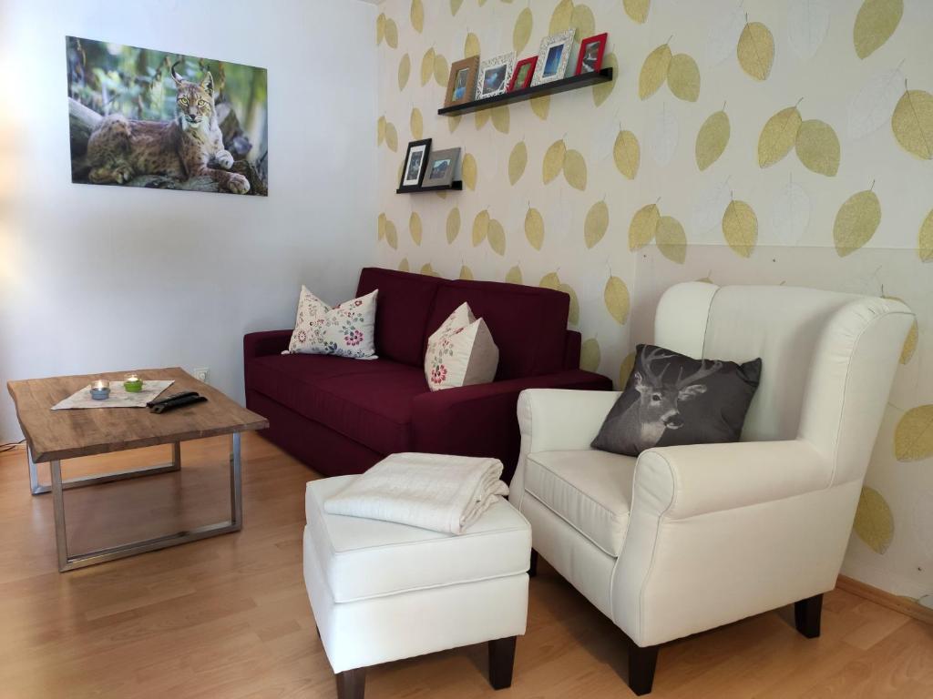 uma sala de estar com um sofá e uma cadeira em Ferienwohnung Harzluchs mit Balkon, Netflix und Sauna im Haus em Hohegeiß