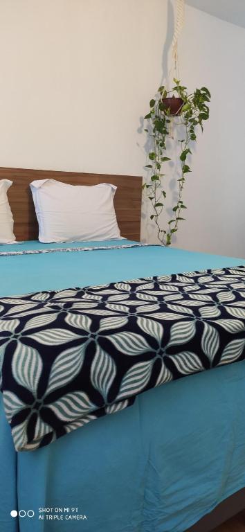 ein Bett mit einer schwarzen und weißen Bettdecke und einer Pflanze in der Unterkunft Casa Índigo- Piscina e Praia em Jacaraípe - 11 hospedes in Jacaraípe