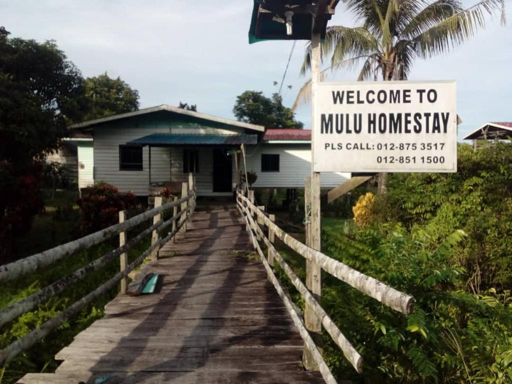 Una casa con un cartello che dice "benvenuti a borbottare il paese" di Mulu Homestay a Mulu