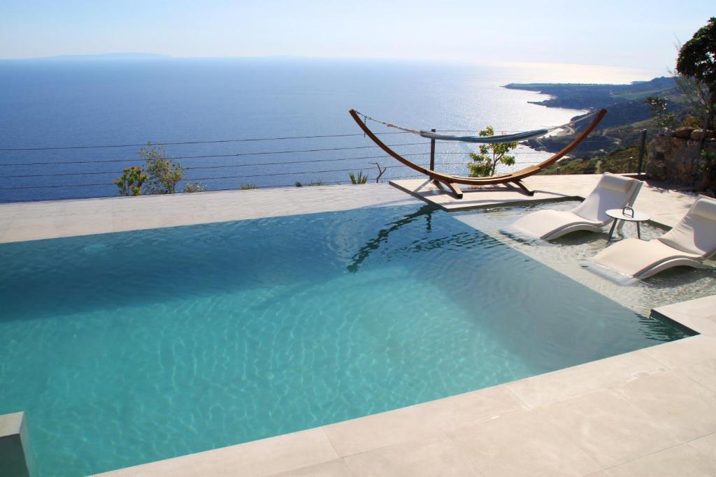 una piscina con sillas y vistas al océano en Anemos Luxury Villas, en Rodakino