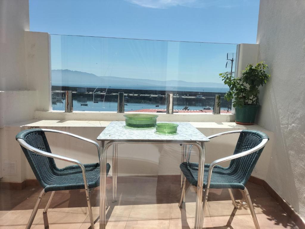 een tafel en 2 stoelen in een kamer met een raam bij Casa Xenoveva in Fisterra