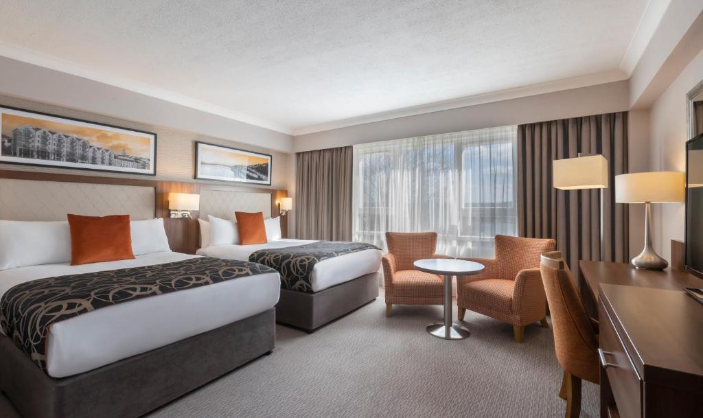 a hotel room with two beds and a desk at Clayton Hotel Silver Springs in Cork