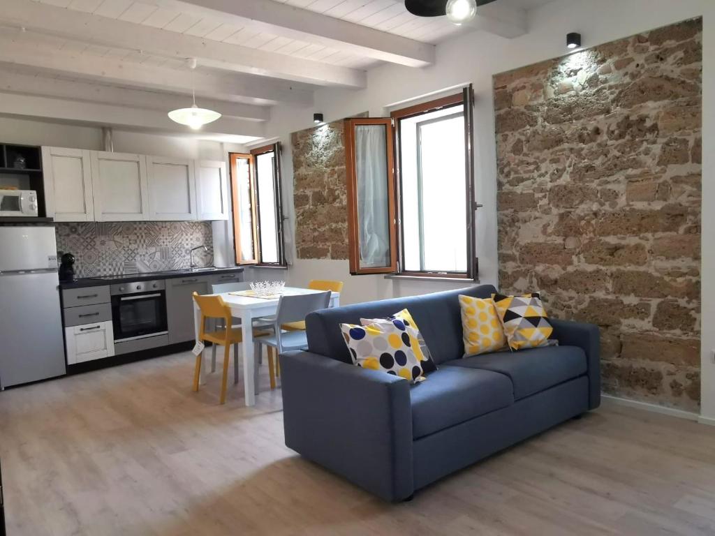 a living room with a blue couch and a kitchen at Casa vacanza il Campanile in Alghero