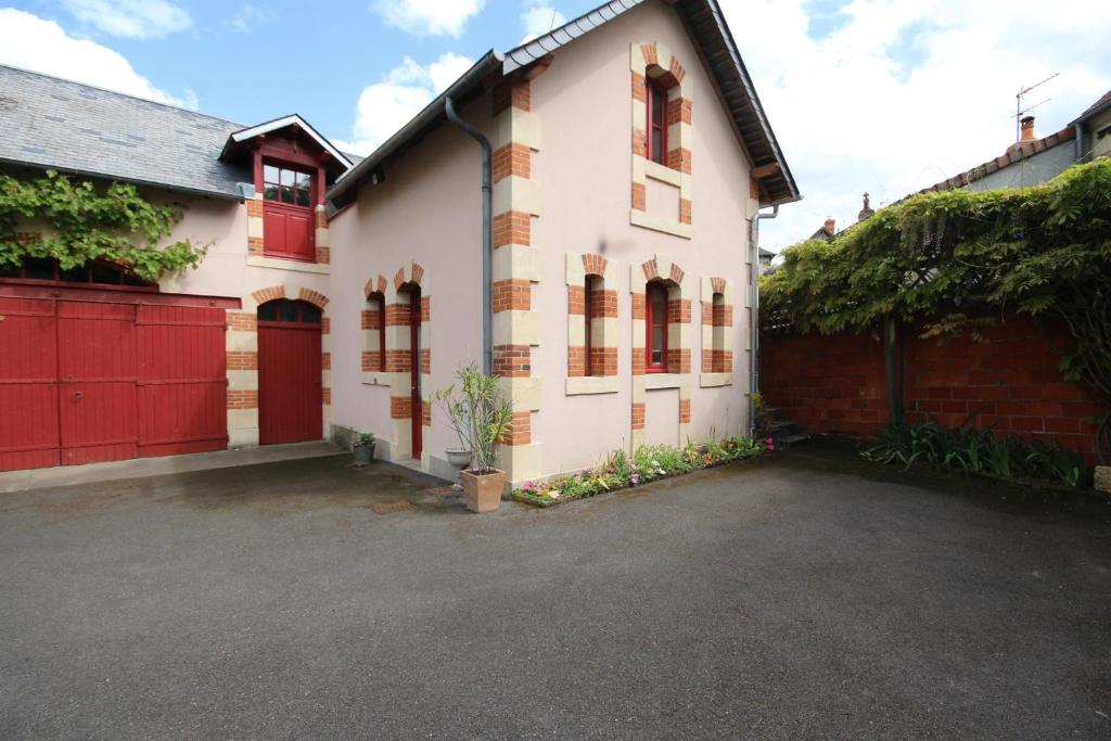 een wit huis met rode deuren en een oprit bij Le Faré Pouguois in Pougues-les-Eaux