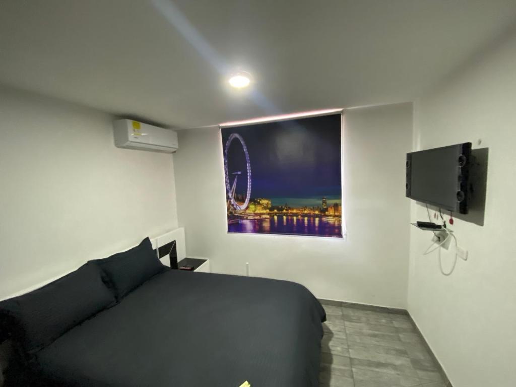 1 dormitorio con cama negra y TV de pantalla plana en apartamento entero zona empresarial cali, en Cali