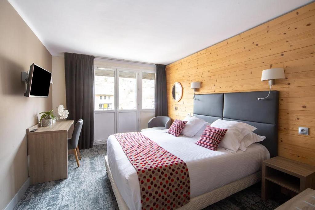 a hotel room with a large bed and a desk at Hôtel Vauban Briançon Serre Chevalier in Briançon