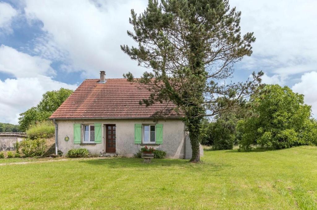 ein kleines weißes Haus mit einem Baum auf einem Feld in der Unterkunft La Tuilerie in Melin