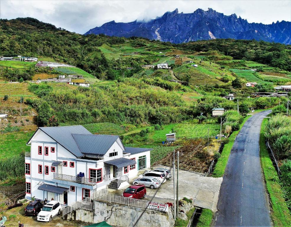 Suang Noh Homestay Kundasang في Kampong Kundassan: منزل على تلة فيه سيارات متوقفة أمامه